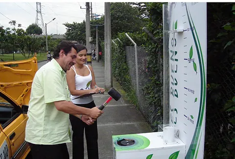 Hombre golpeando un juego de fuerza de marca acompañado de una promotora