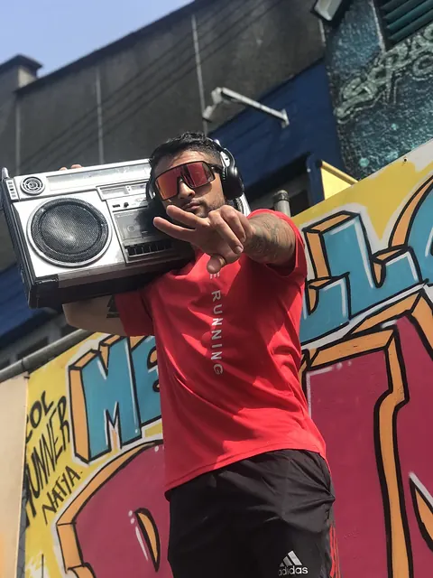 Lanzamiento urbano con un bailarín y una grabadora al hombro frente a un mural de grafiti
