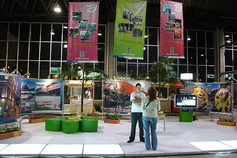 Montaje de feria en un pabellón con pendones colgantes y módulos de exposición