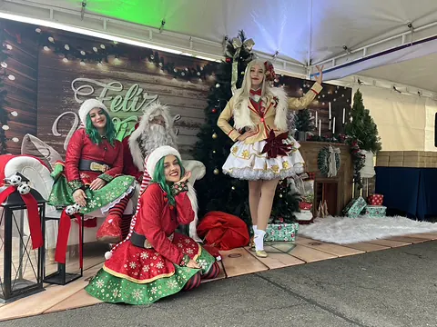 Personajes navideños con vestuario rojo y blanco en un set decorado
